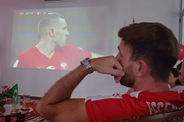 Fotografia colorida de um homem assistindo jogo do Brasil contra a Sérvia na Embaixada